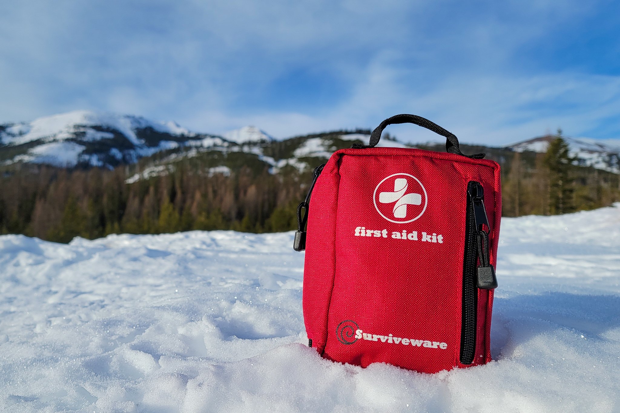 Closeup of the Surviveware Small First Aid Kit in a snowy mountain scene