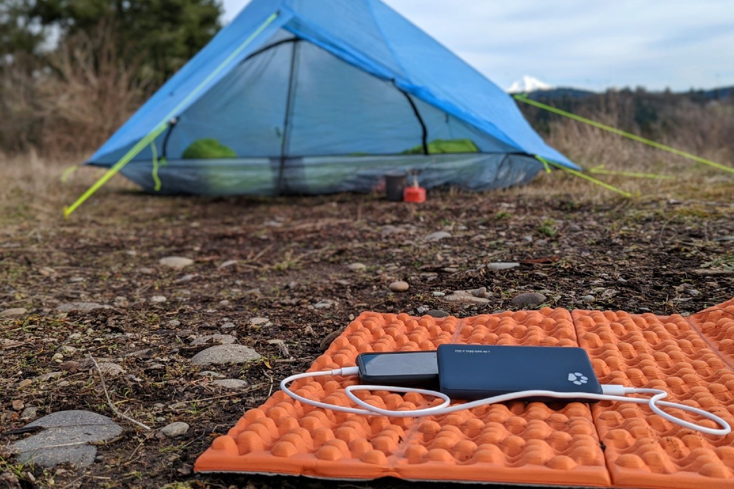 The Iniu Megapower 10000 power bank sitting on a foam pad with a tent in the background