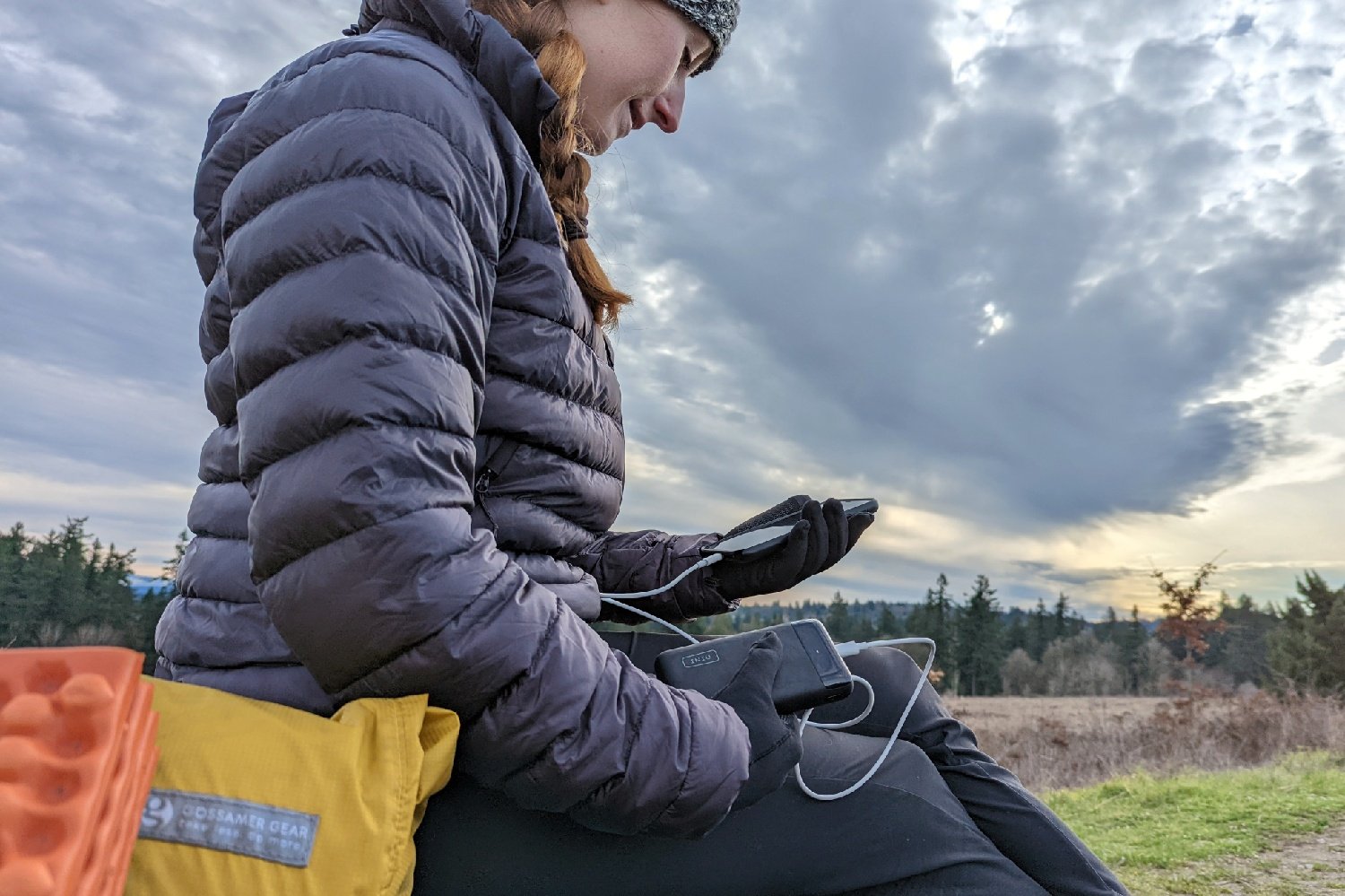 A hiker looking at their phone that's plugged into the Iniu 20000 PD Power Bank
