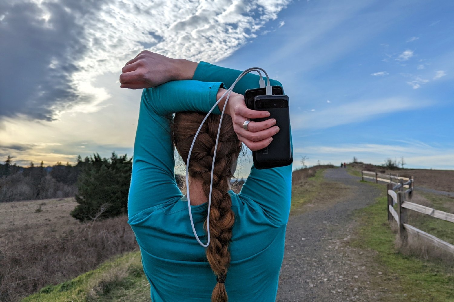 A hiker stretching - theyre holding the Iniu 20000 PD power bank and a phone in one hand