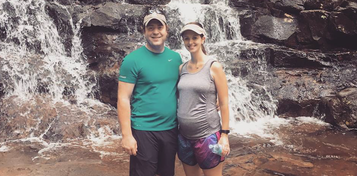 A pregnant woman standing at a waterfall